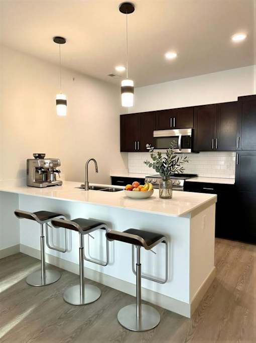 A kitchen with a white countertop and black bar stools.