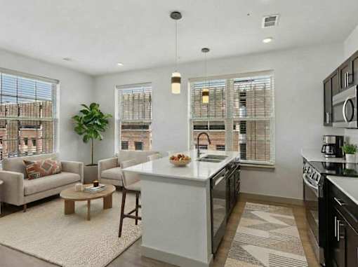 A modern kitchen with a large island, a dining table with chairs, and a view of the city.