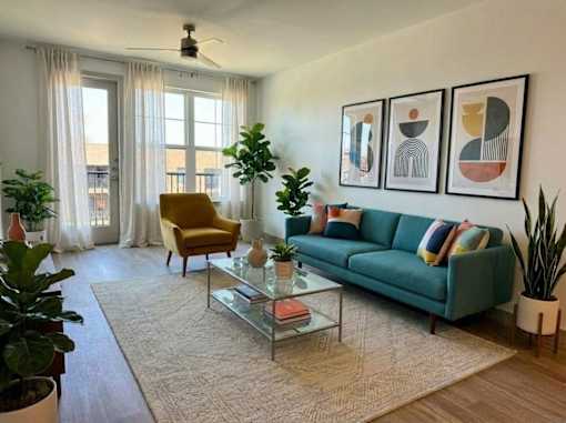 A living room with a green couch, a yellow chair, and a glass coffee table.