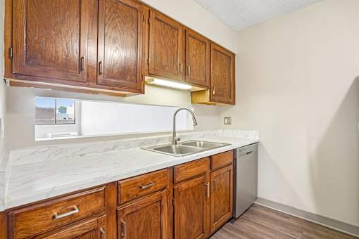 Irvine Park Towers kitchen with wood cabinets, light countertops, sink and dishwasher