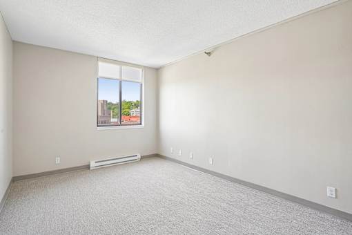Bright Irvine Park Towers apartment bedroom with large window and carpeted flooring