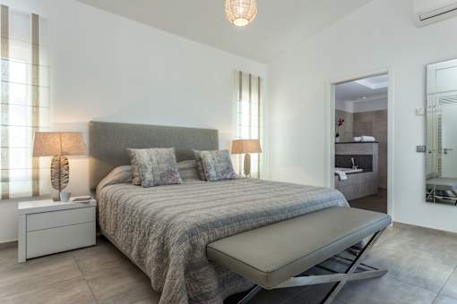 A bedroom with a bed, nightstands, and a chair.
