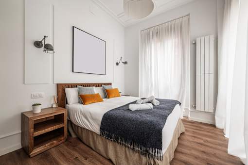 A bedroom with a large bed and a wooden nightstand.