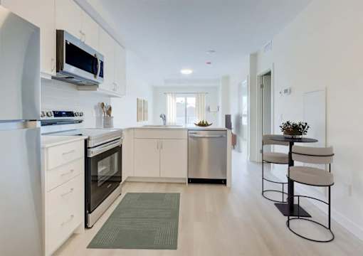 A modern kitchen with white cabinets and stainless steel appliances.at Sylk Towers, Ontario