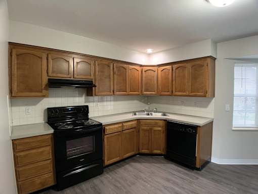 A kitchen with wooden cabinets and black appliances.