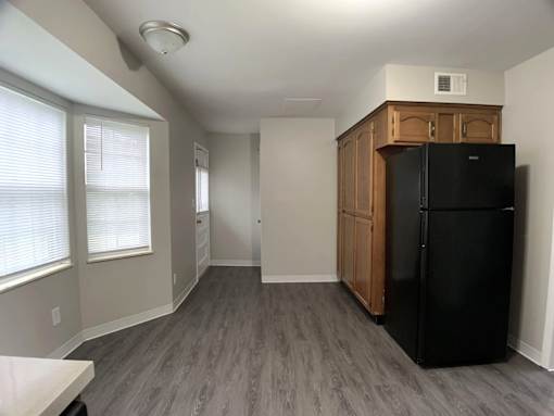 A kitchen with a black fridge and wooden cabinets.