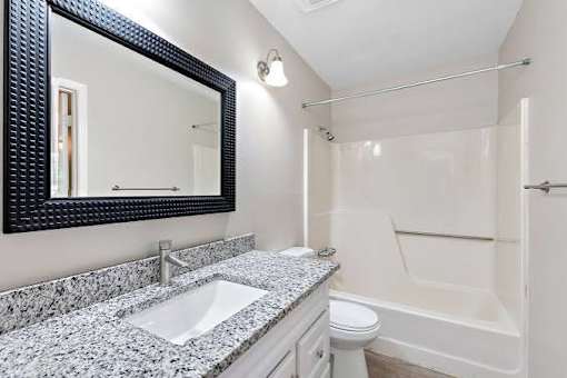 A bathroom with a sink, mirror, and bathtub.