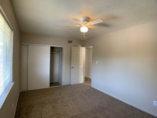 A room with a ceiling fan and carpeted floor.
