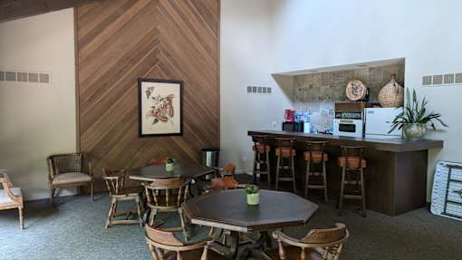 A dining room with a wooden table and chairs and a bar area.