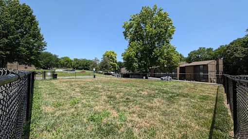 A grassy field surrounded by a fence with a building in the background.