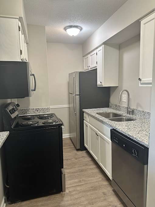 A kitchen with black appliances and white cabinets.