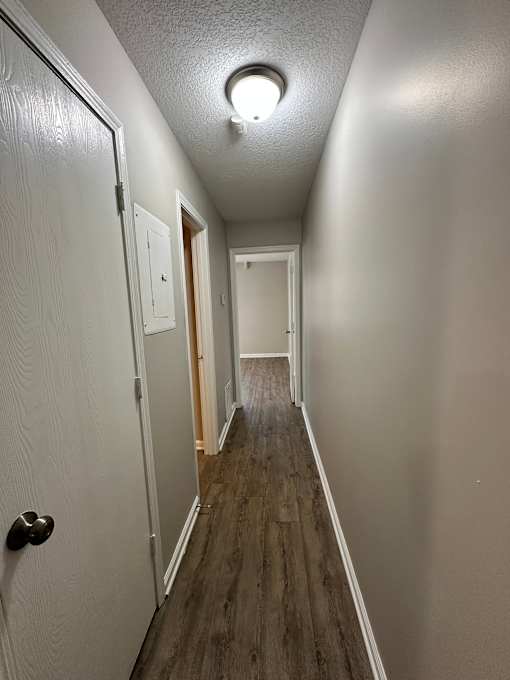 A long hallway with a door on the left and a light on the ceiling.