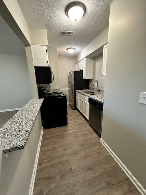 A kitchen with black appliances and white cabinets.