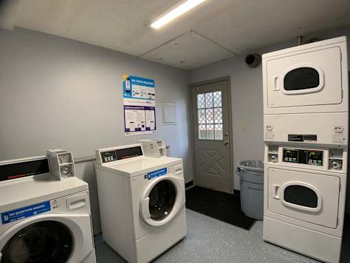 A laundromat with washers and dryers and a sign on the wall.
