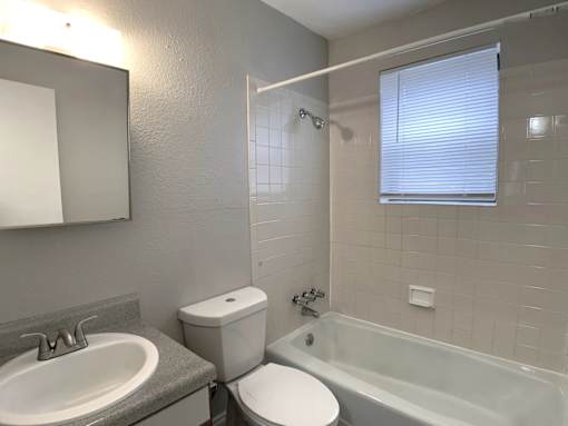 A bathroom with a toilet, sink, and shower.