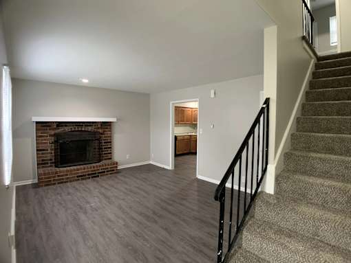 A living room with a fireplace and a staircase.