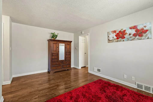 A room with a red rug and a wooden cabinet.