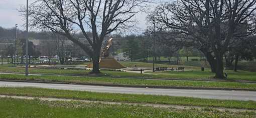A park with a grassy area, trees, and a bench.