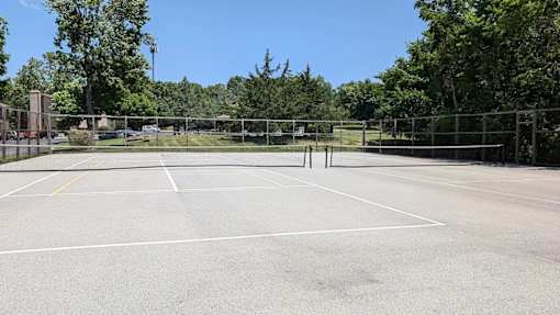 A tennis court surrounded by a fence and trees.