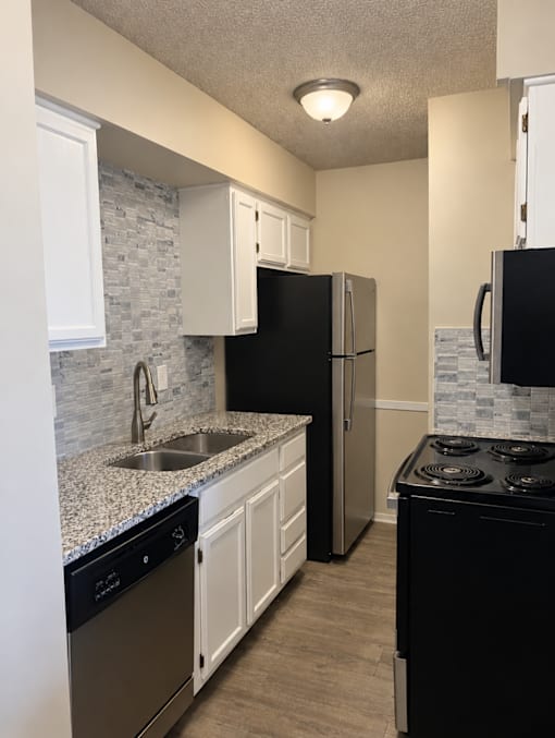 A kitchen with black appliances and white cabinets.