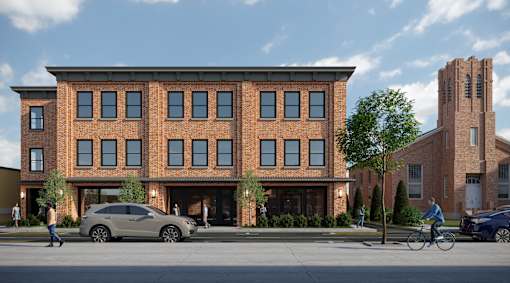 A modern brick building with a parking lot in front.