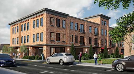A street view of a red brick building with cars parked in front and people walking on the sidewalk.