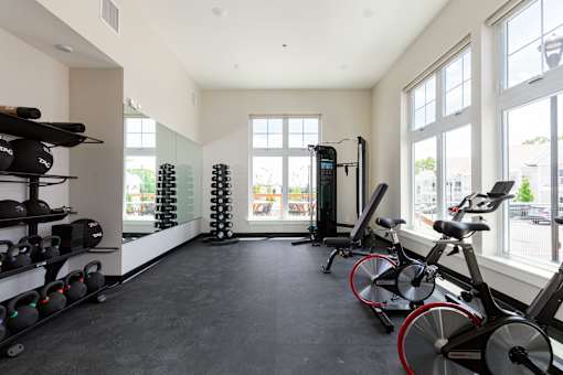 A spacious gym with a row of exercise bikes and a rack of kettlebells.