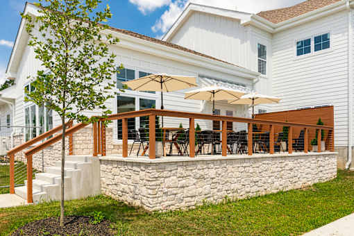 A white house with a stone wall and a tree in front.