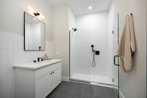 A bathroom with a white counter and a glass shower stall.