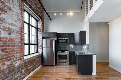 A kitchen with a brick wall and wooden floors.