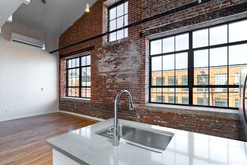 A kitchen with a large sink and a window overlooking a building.