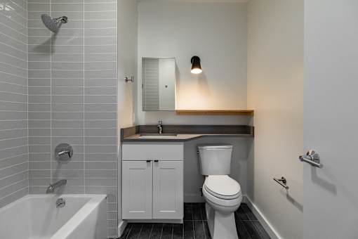 A white toilet is in a bathroom with a white tub and sink.