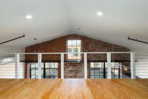 A room with a wooden floor and a brick wall with a window.