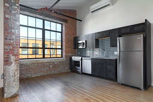 A kitchen with a brick wall and wooden floors.
