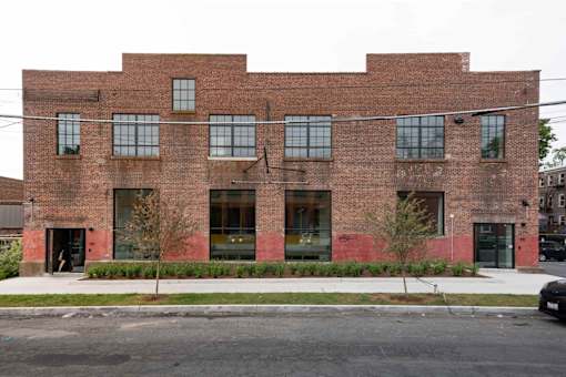 A red brick building with a black car parked in front.