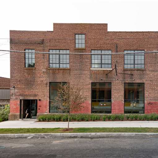 A red brick building with a tree in front.