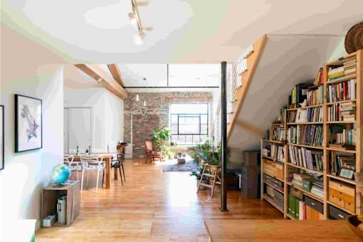 A room with a large bookshelf filled with books and a table with chairs in the background.