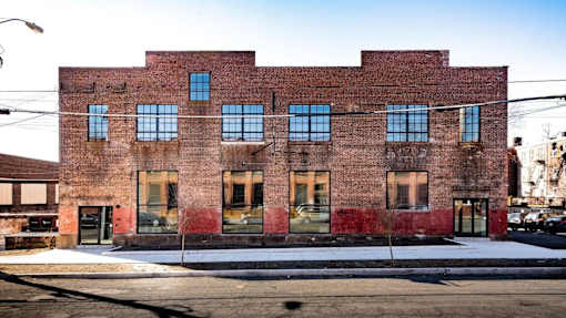 A red brick building with a green door and windows.