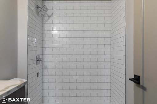 A white tiled shower in a bathroom.