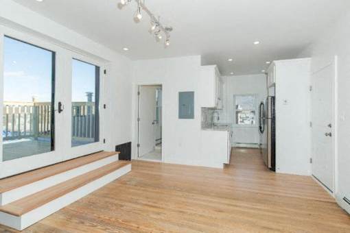 A spacious, well-lit room with wooden floors and white walls.