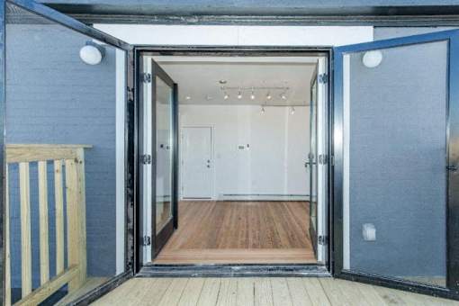 A room with a wooden floor and white walls is visible through an open door.