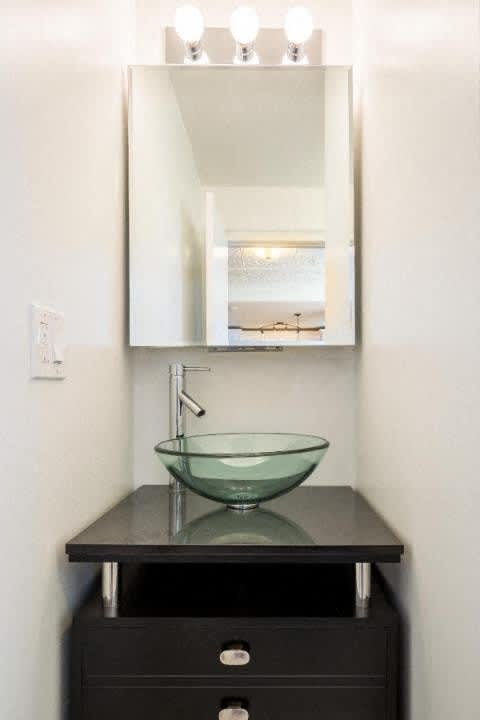 A bathroom vanity with a glass bowl sink and a mirror above it.