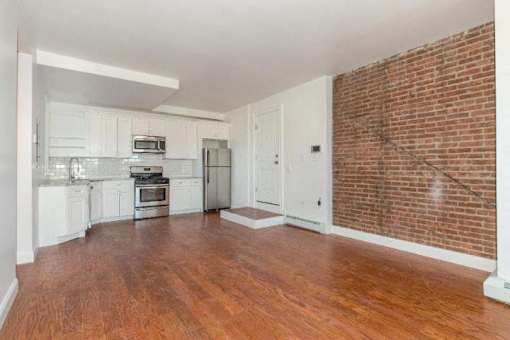 A kitchen with white cabinets and a brick wall.