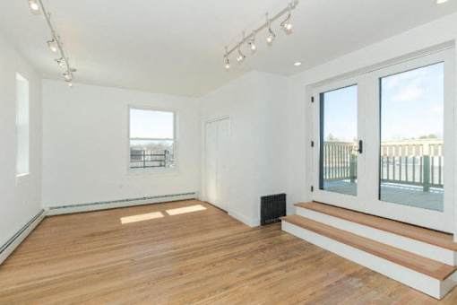 A room with white walls and wooden flooring, with a window and a door.