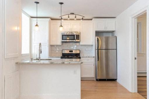 A kitchen with a refrigerator, microwave, and oven.