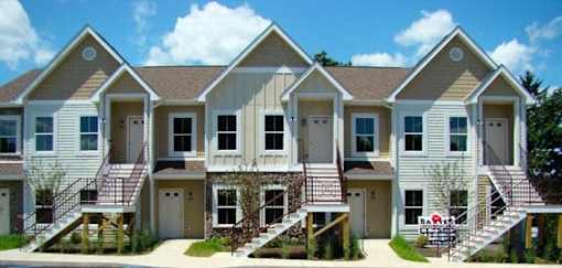 A row of townhouses with a red lawn chair in the front yard.