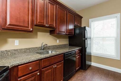 A kitchen with brown cabinets and black appliances.