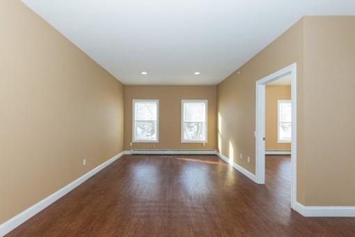 A room with wooden floors and three windows.