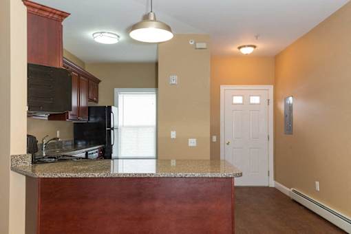 A kitchen with a granite counter top and a black refrigerator.