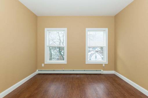 A room with two windows and wooden floors.